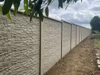clôture en béton imitation pierre dans sa teinte sable naturel sur une grande longueur , en denivelé, avec chaperon de plaque