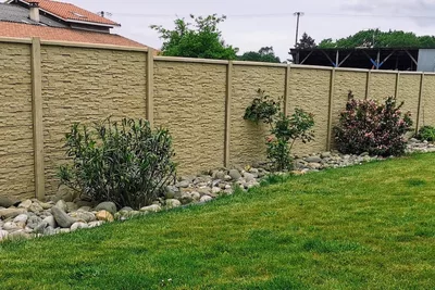 clôture en béton imitation pierre simple face de couleur sable naturel avec chaperon lisse au bord d'un jardin